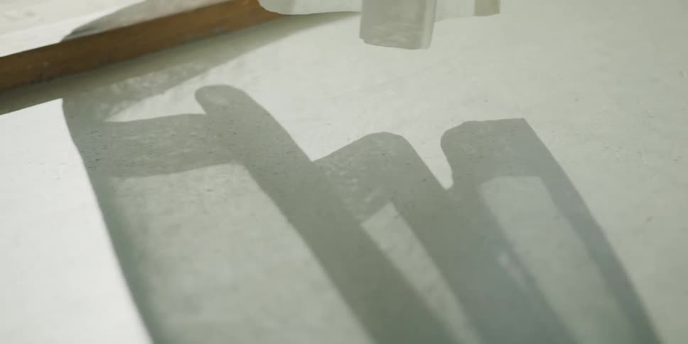 The shadow of a sheer white curtain dances on a sunlit surface as the fabric sways in a gentle breeze