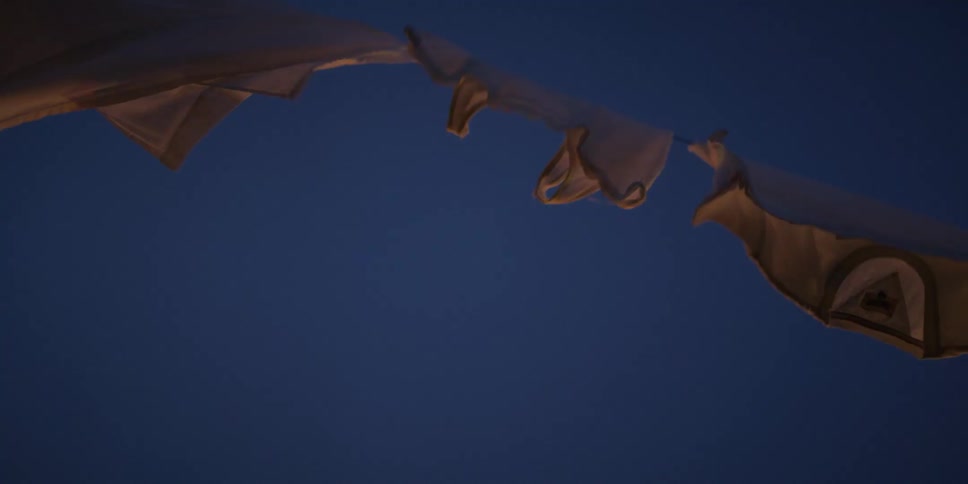 Ethereal white laundry dances in slow motion on a clothesline against the twilight sky