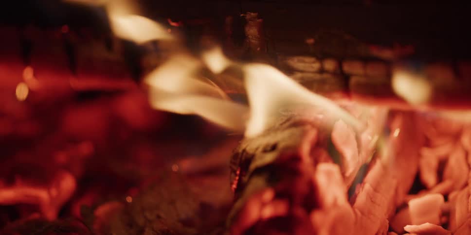Warmth and comfort emanate from this close-up slow-motion shot of a crackling fire and its glowing embers