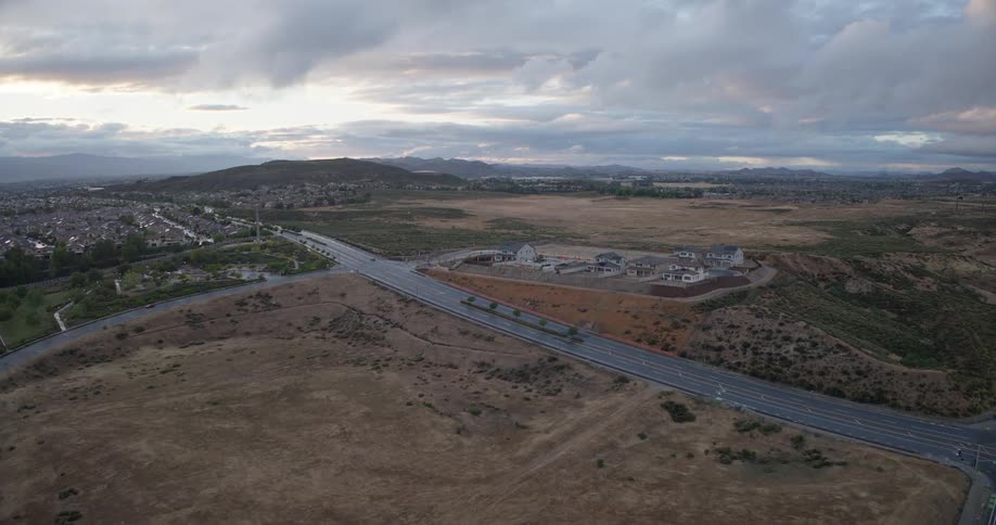 An aerial time-lapse captures the construction of a new suburban housing development, from empty lots to nearly completed homes, under a cloudy sky