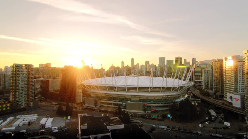 An aerial view reveals Vancouver's BC Place stadium and surrounding cityscape during a beautiful golden hour sunset