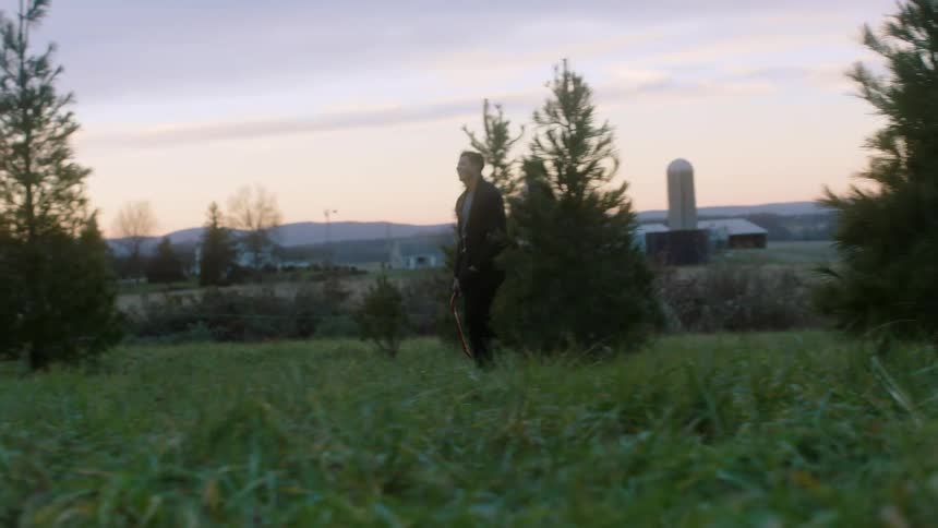 A man and woman walk through a rural area at sunset