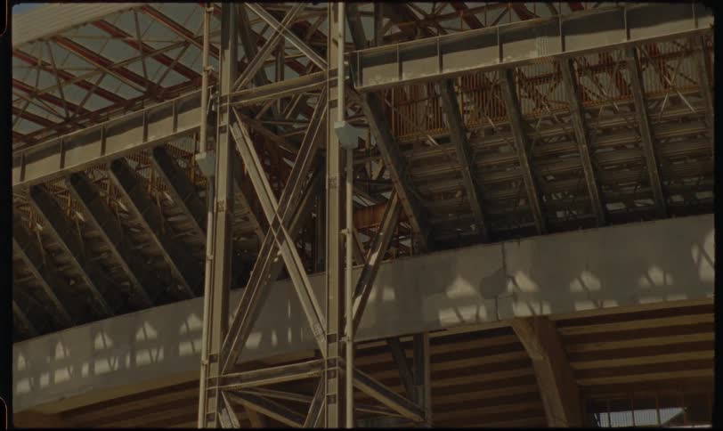 A static timelapse shot captures the movement of shadows across the architectural details of a large, empty warehouse