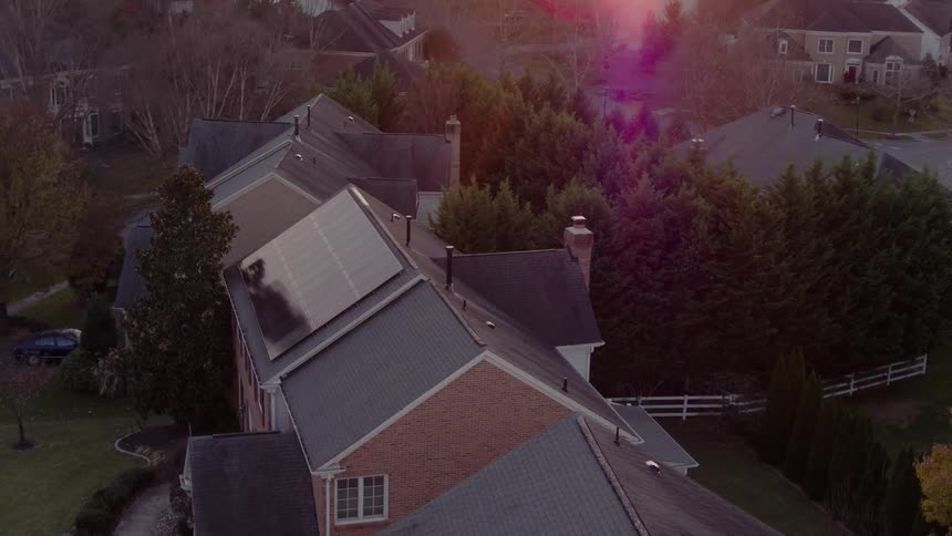 Solar panels sit atop one house in a suburban setting