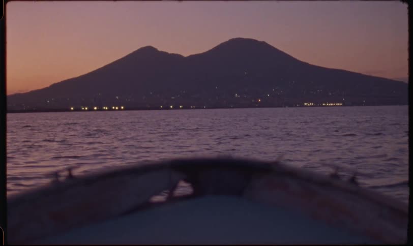 A serene boat ride on the Bay of Naples at dusk offers a stunning view of Mount Vesuvius and the glowing coastline