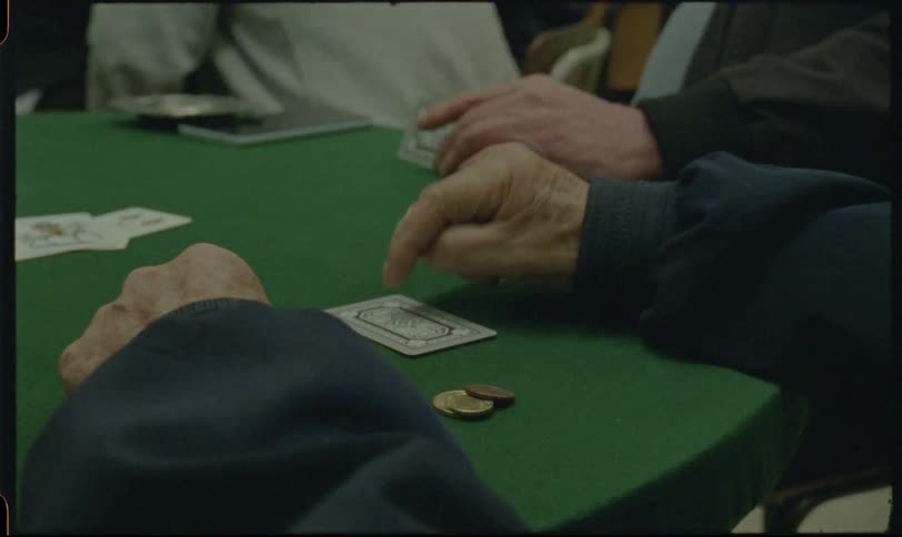 A vintage-style, first-person shot of aged hands playing a traditional card game on a green felt table