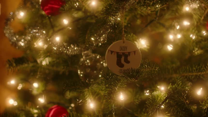 A woman hangs a christmas ornament on a tree
