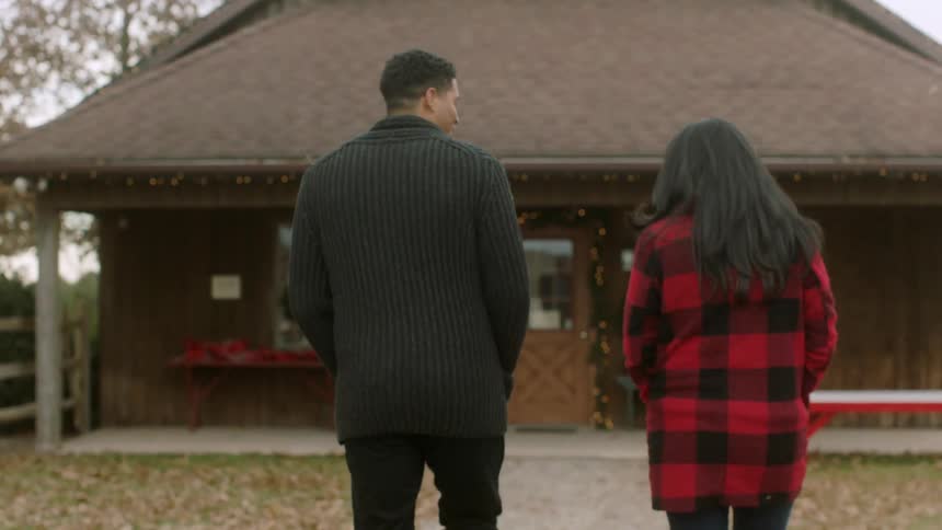 A man and woman approach a building in a rural area