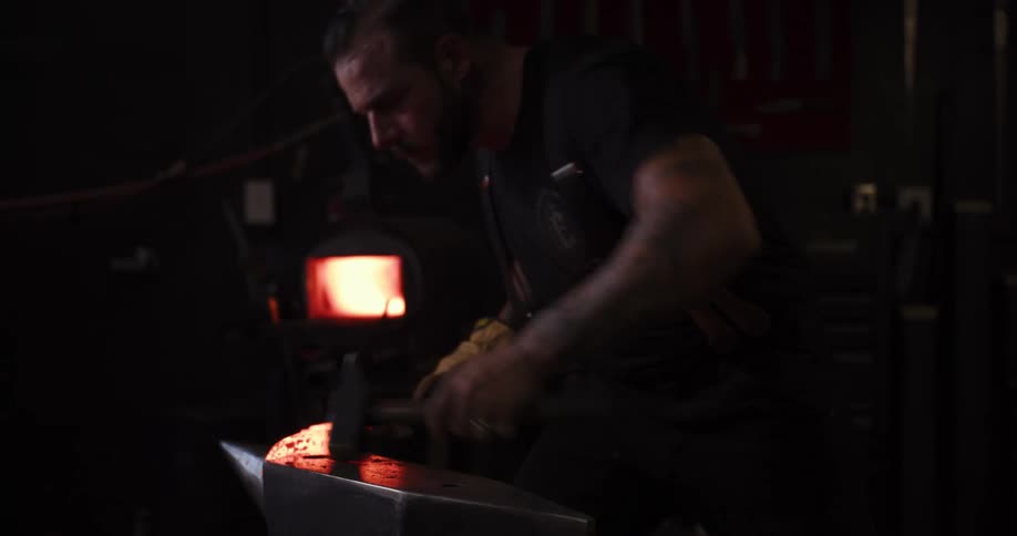 In a dimly lit workshop, a strong blacksmith forges a glowing piece of metal, hammering it into shape on an anvil
