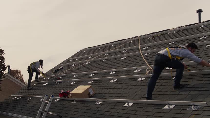 Two men work on a roof