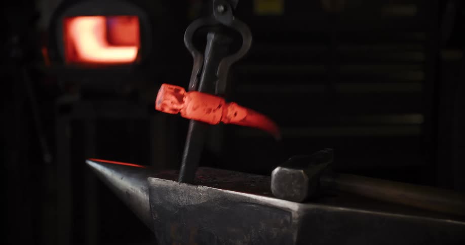 A craftsman forges a custom axe head, hammering the glowing red-hot steel on an anvil in a dark workshop