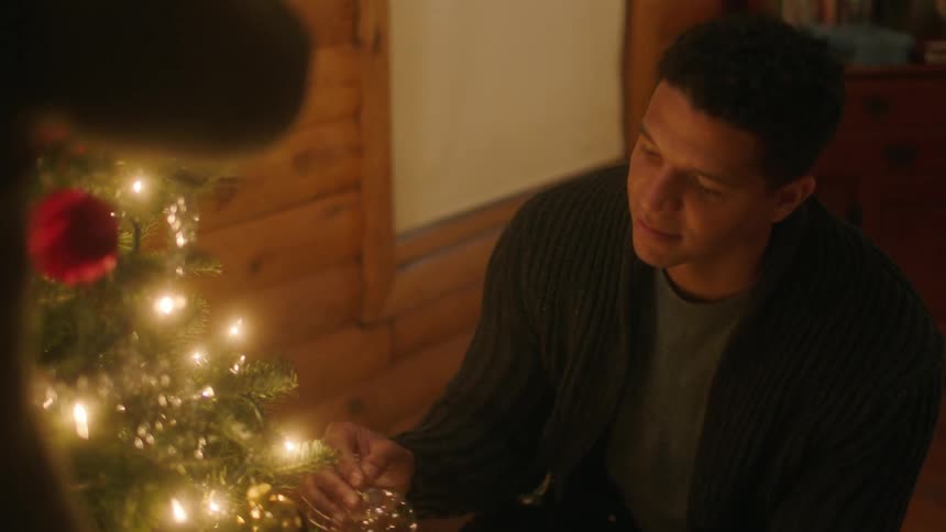 A man and woman decorate a christmas tree