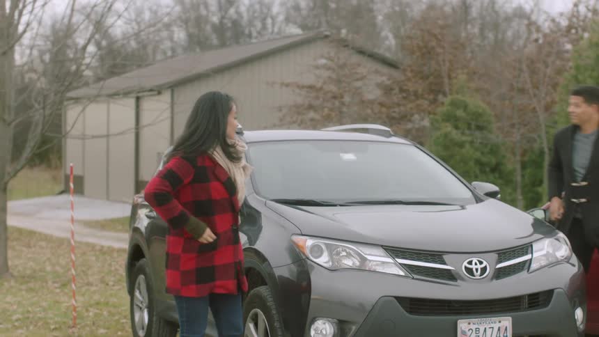 Man and woman get out of car in parking lot and walk off smiling