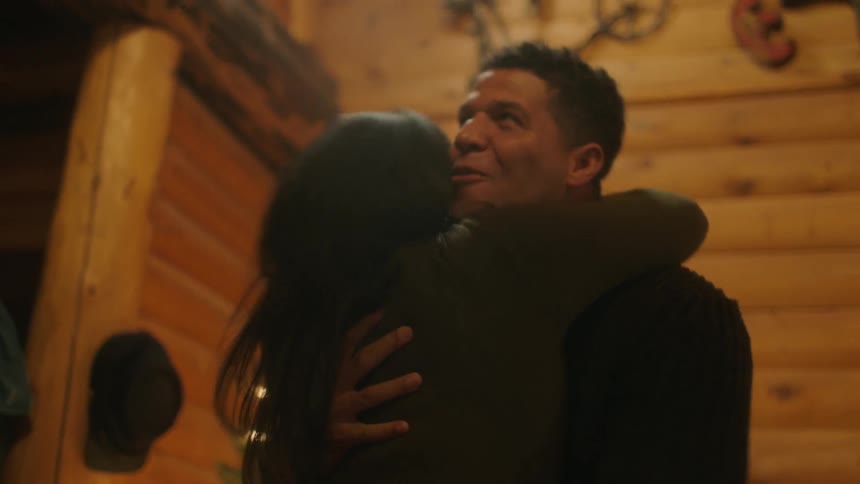 A man and woman embrace and laugh near a christmas tree