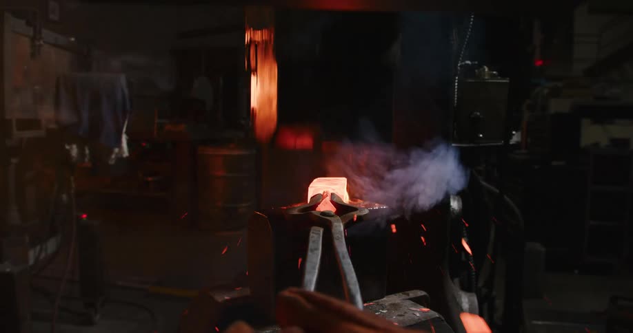 Intense close-up of a blacksmith forging a billet of glowing steel with a power hammer, sending sparks and flames flying
