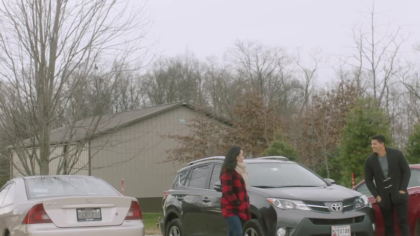 Man and woman get out of car in parking lot and walk off smiling
