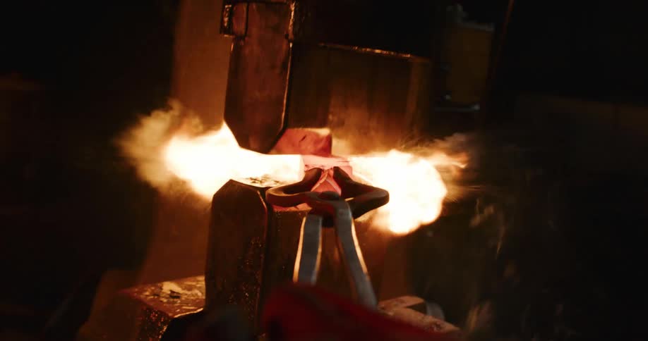 First-person perspective of a blacksmith forging a glowing hot piece of steel with an industrial power hammer, creating intense sparks and fire in a dark workshop