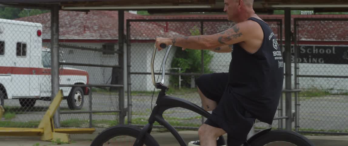 Man rides bicycle down neighborhood street