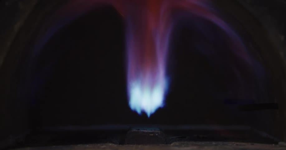 Slow motion closeup of a powerful gas burner being ignited by a torch inside a furnace