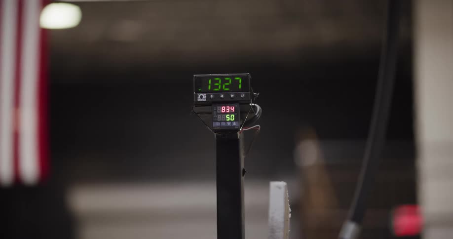 An industrial digital counter displays green and red numbers as it counts up in a workshop