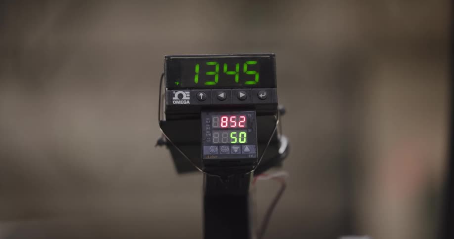 A close-up of a digital counter and meter displaying changing numbers in an industrial setting