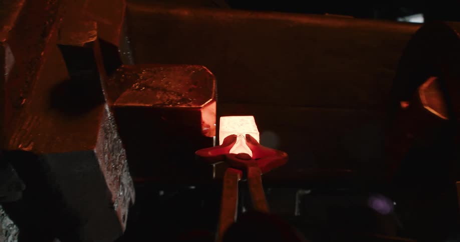 POV shot of a blacksmith pulling a glowing hot piece of metal from a forge and shaping it with a powerful industrial hammer