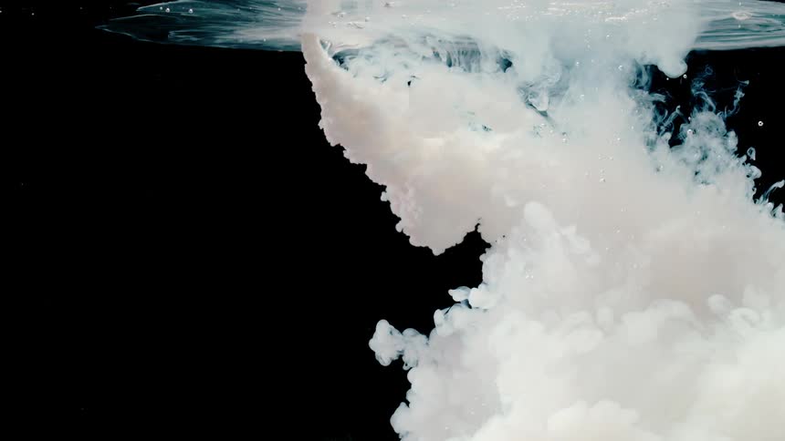 A white liquid is pouring into another liquid and spreading out