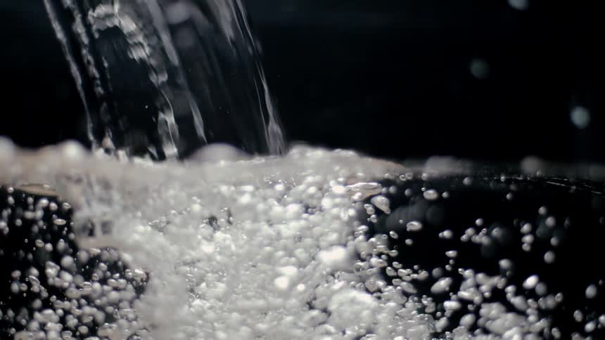 Water pours into a container sending bubbles swirling through the liquid