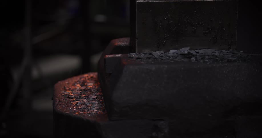 Water cools a hot anvil, creating steam and making embers glow in a dark blacksmith's workshop