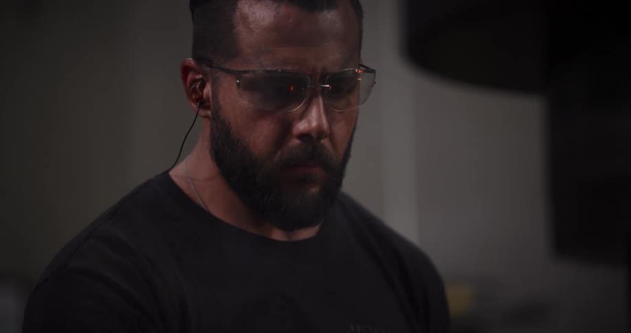 Intense close-up of a focused blacksmith with fire reflected in his safety glasses as he works in his forge