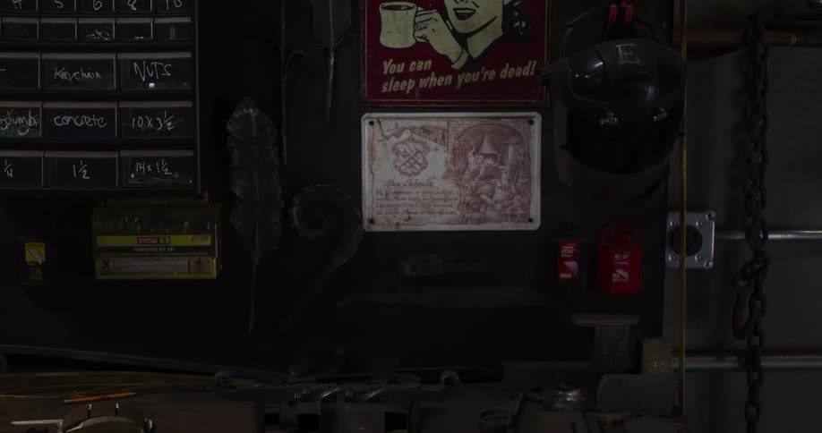 A tilt-down shot reveals the interior of a blacksmith's workshop, from the decorated wall to the tool-covered workbench