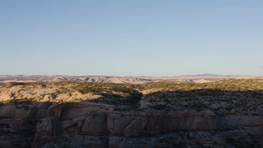 A smooth tracking shot reveals the vast, sun-kissed canyon landscape of the American Southwest during a scenic drive