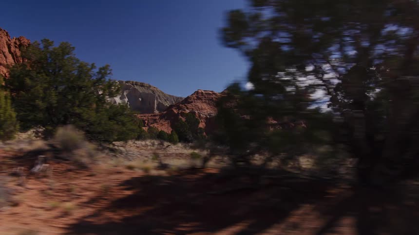 A scenic tracking shot reveals the majestic red rock formations and canyons of the American Southwest on a beautiful sunny day