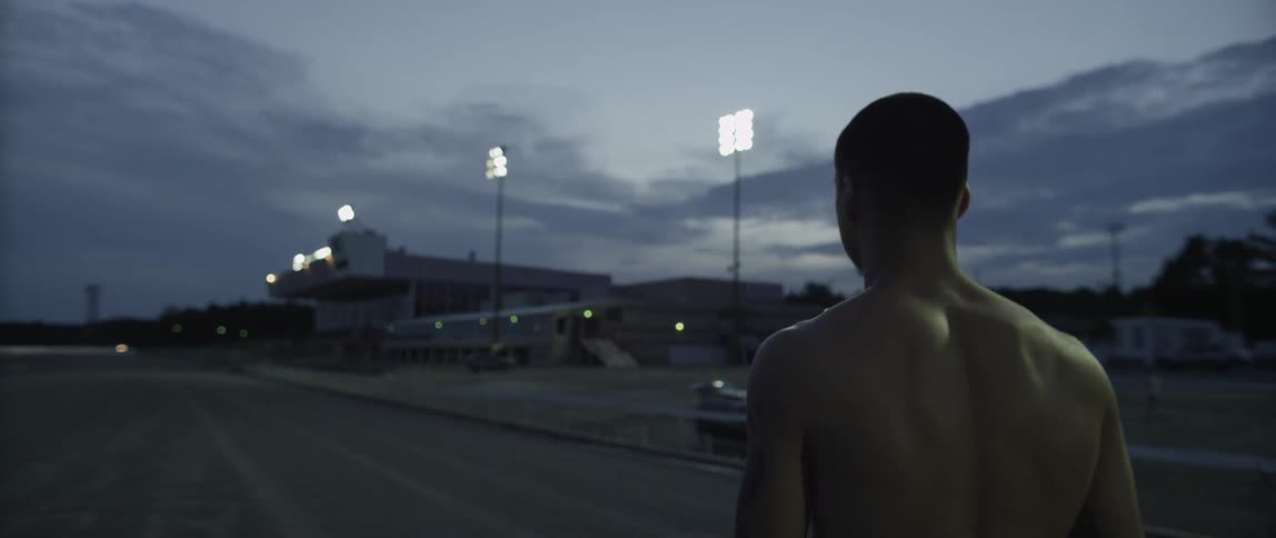 Man walking shirtless outside at dusk