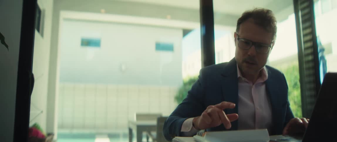 A happy businessman in glasses calculates finances on his calculator while working from his modern home office