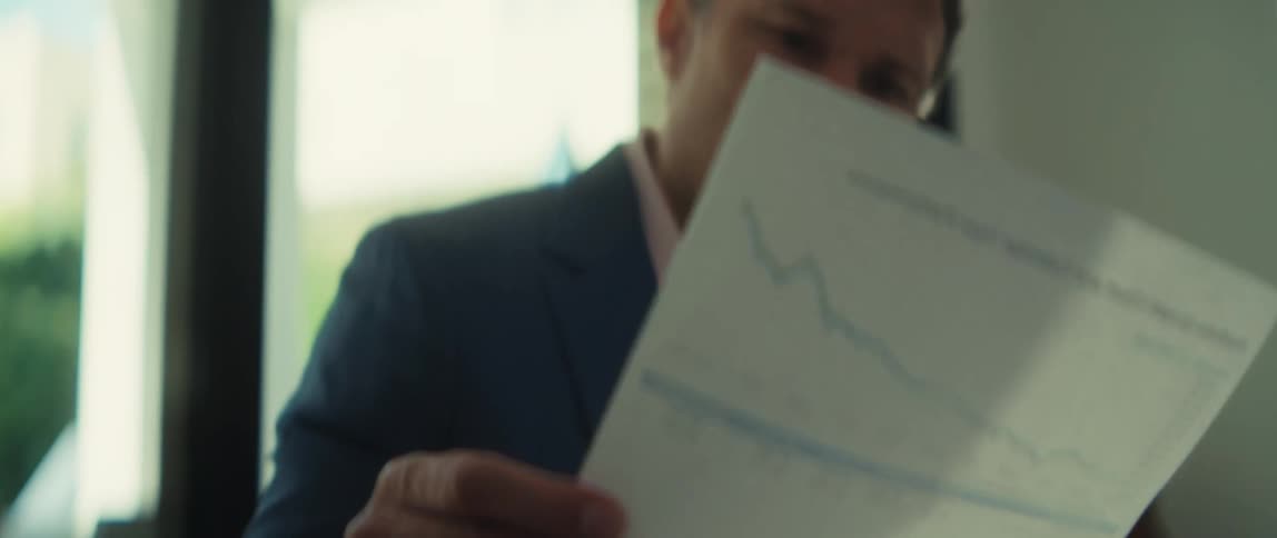 A concerned businessman reviews a financial report showing a significant downturn in performance
