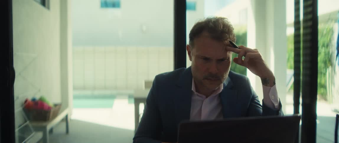 Close-up of a concerned businessman working from home, deeply engrossed in his laptop as the camera slowly zooms in