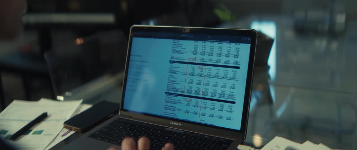 Over-the-shoulder view of a person analyzing a detailed financial spreadsheet on their laptop computer