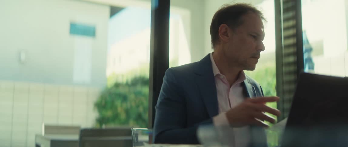 A serious businessman analyzes a bar chart before working on his laptop in a bright, modern office