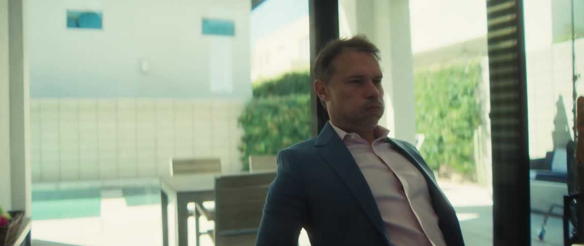 An overwhelmed businessman takes off his glasses in frustration while working on his laptop from his modern home
