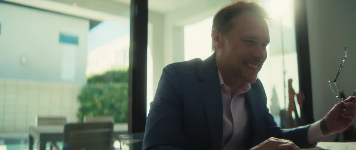 A successful businessman working on his laptop in a modern home office smiles as the camera slowly zooms in