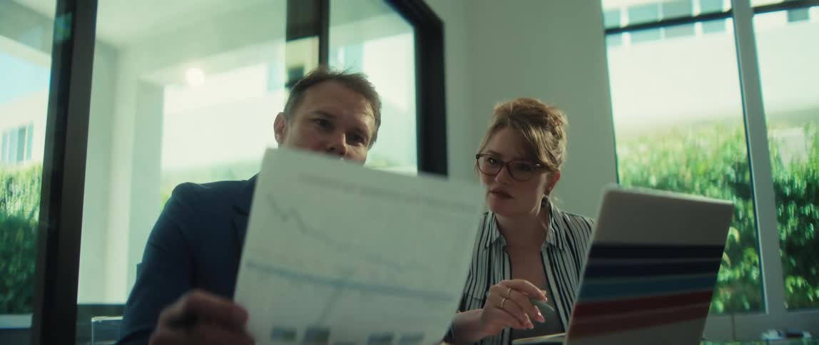 A businessman and businesswoman review financial data on a chart during a collaborative meeting in their office