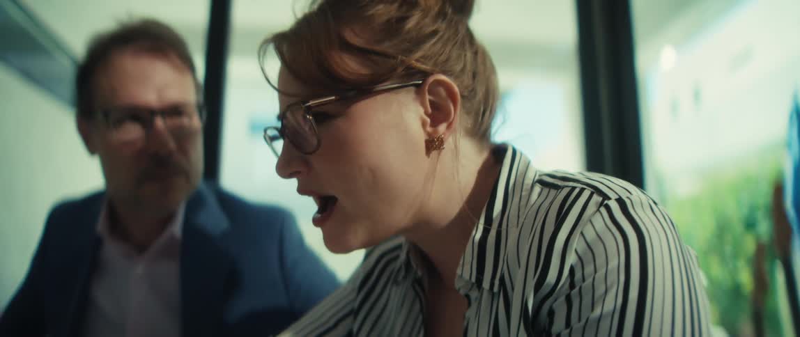 A businesswoman explains project details to her male colleague during a collaborative meeting in a bright, modern office