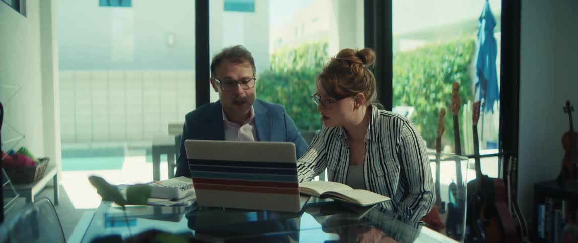 A man and woman collaborate on a project, reviewing information together on a laptop in a modern, sunlit office space
