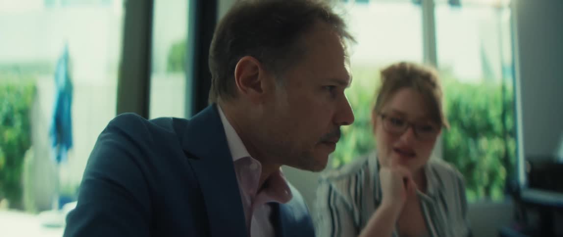 In slow motion, a businessman points to a financial chart while explaining the data to a smiling female colleague in a sunlit office