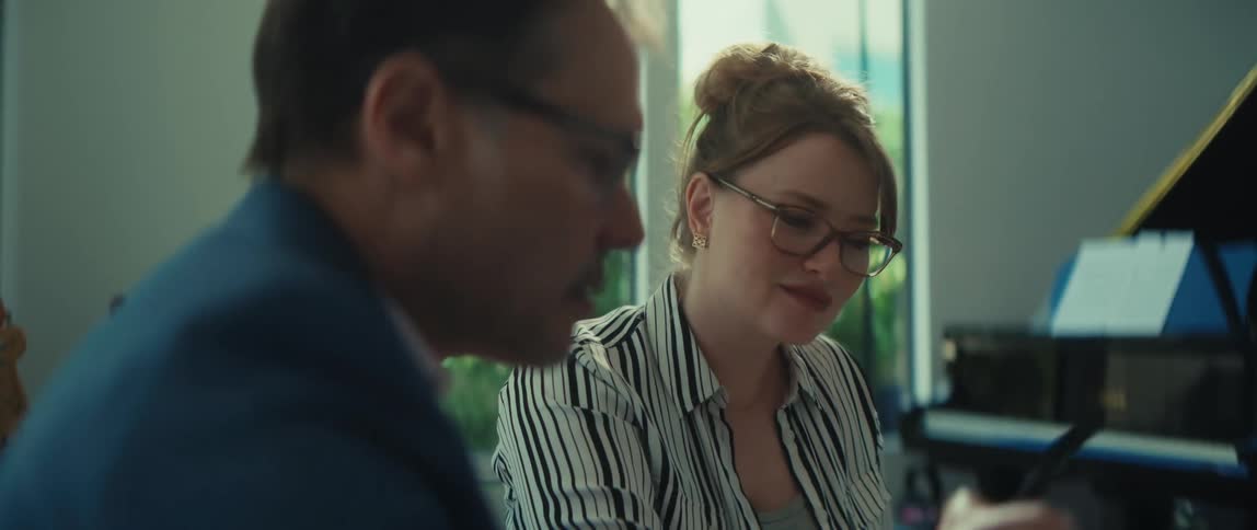 A male and female professional with glasses collaborate in a naturally lit modern office