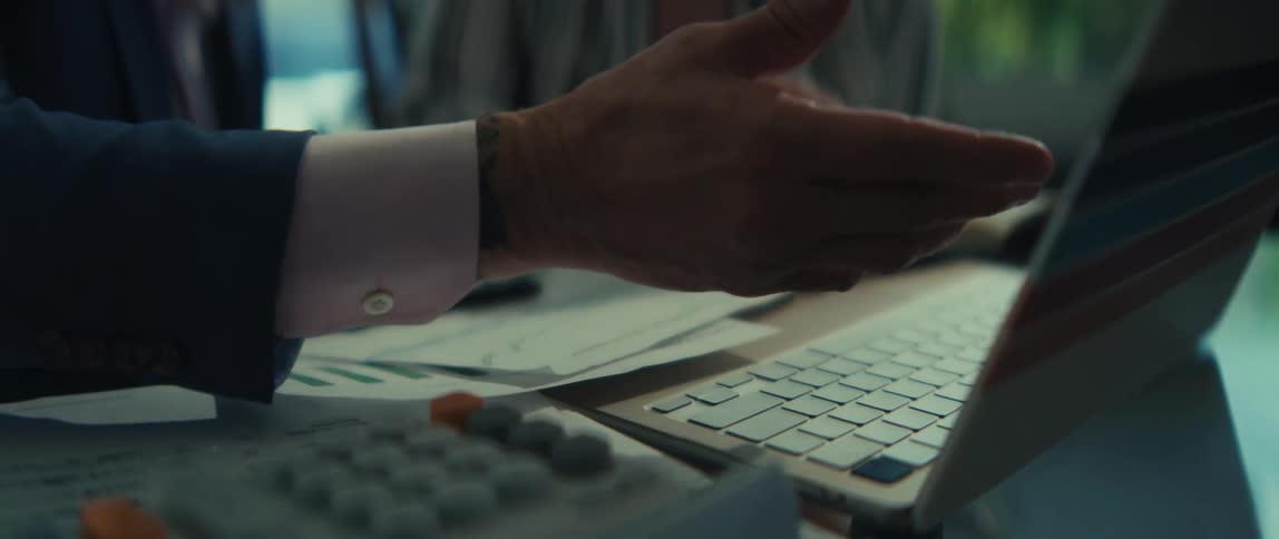 A financial advisor in a suit explains financial data on a laptop to a female client during a meeting