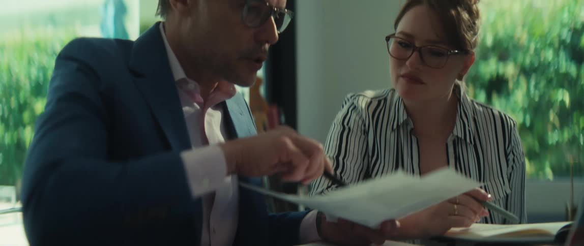 A male real estate agent explains the final paperwork to a female client before handing over the keys to her new home