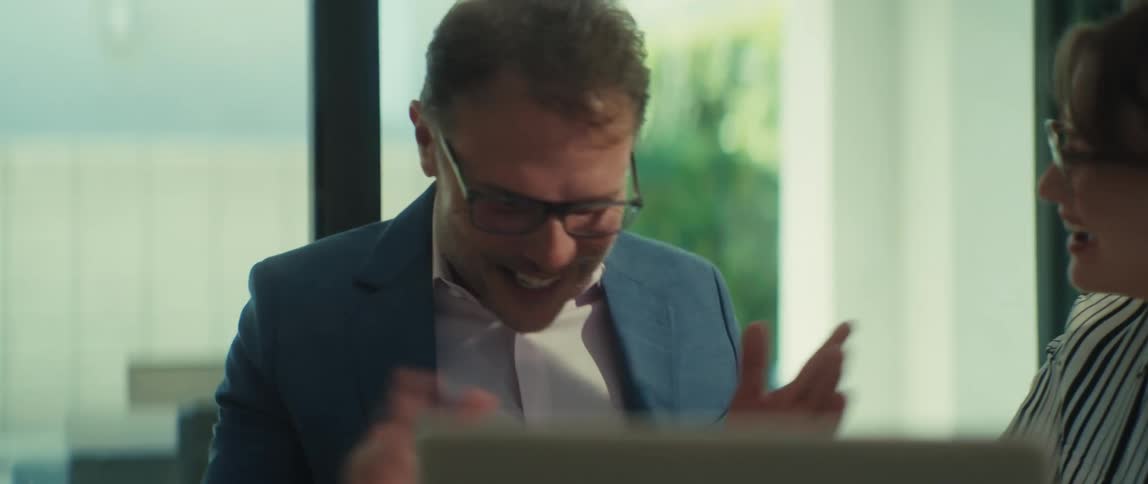 A man and woman collaborate on a project in a modern office, laughing and engaging in a lively discussion