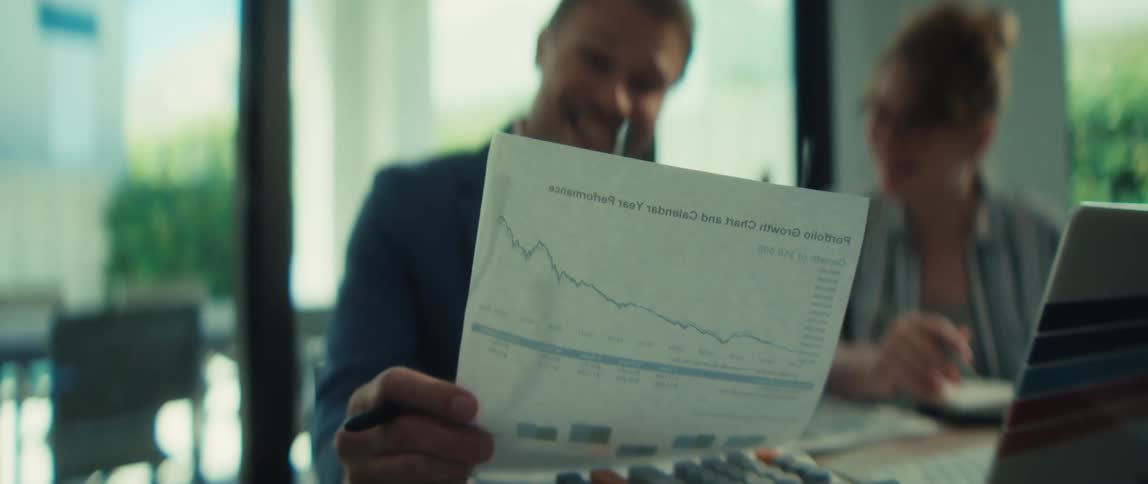 Male and female business partners intently analyze a performance chart, discussing strategies in a modern, naturally lit office